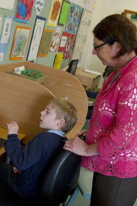 Boy in front of a computer with a teacher
                  alongside