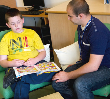 A boy reads a comic with his teacher]