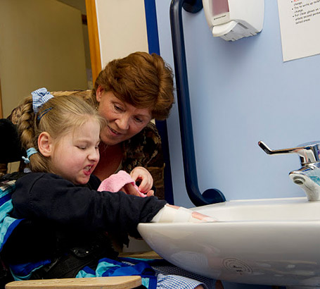 A teacher helps a girl wash her
                  hands