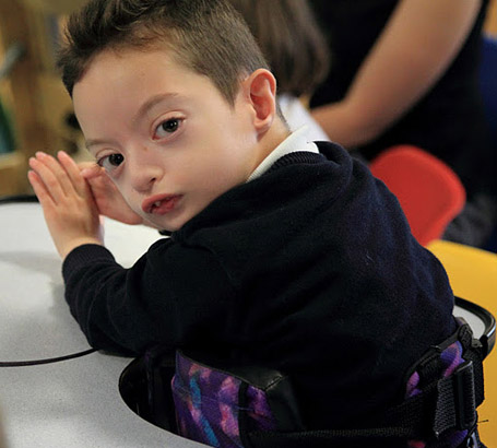 A boy in a standing support looks at the
                  camera