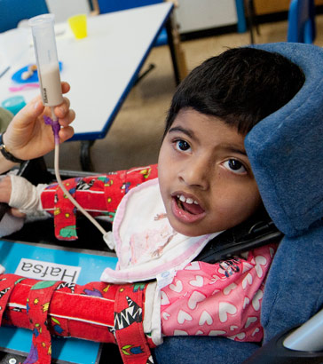 A carer hold's a boy's feeding tube