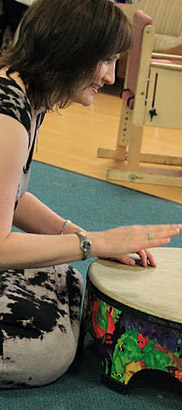 A girl and her teacher play a large drum