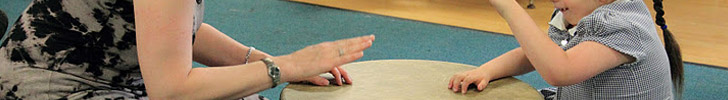 A girl and her teacher play a large drum