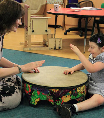 A girl and her teacher play a large drum