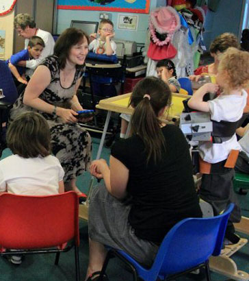 A group of adults and children sit in
                  a circle]