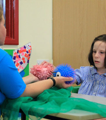 A teacher helps a girl stick a card to a
board
