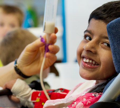 A teacher holds a boy's feeding
                  tube