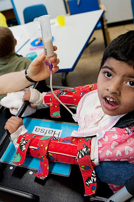 A teacher holds a child's feeding
                  tube