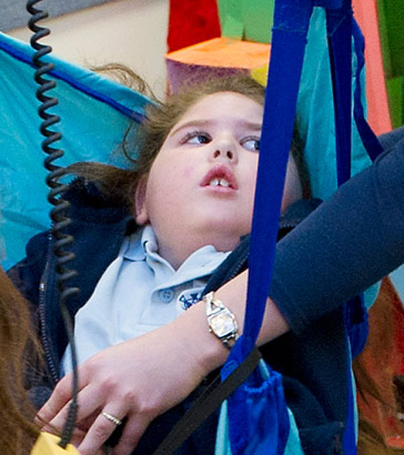 Two carers use specialised equipment
to lift a child into a wheelchair