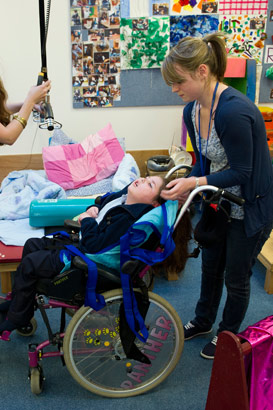 Two carers ensure that a child is
comfortable in a wheelchair