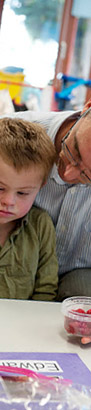 A carer holds two food items in
                  front of a boy