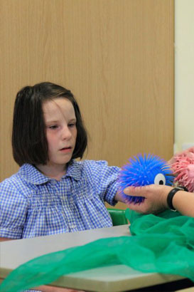 A teacher helps a girl stick a card to
                  a board