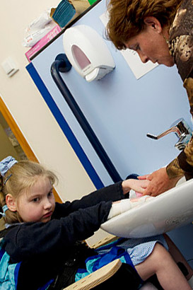 A teacher helps a girl wash her
                  hands