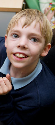 A boy sitting in front of a computer
                  smiling at the camera