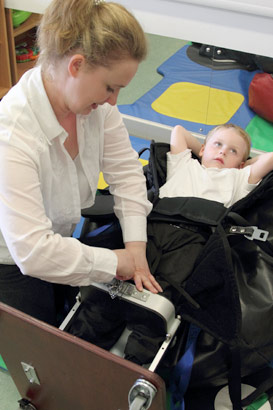  A carer helps a boy into a standing frame