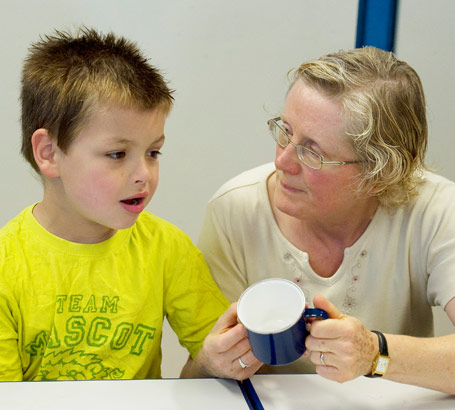 Disabled boy and teacher try to
name an object.