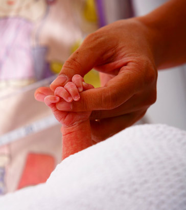 Newborn holding mother's
finger.