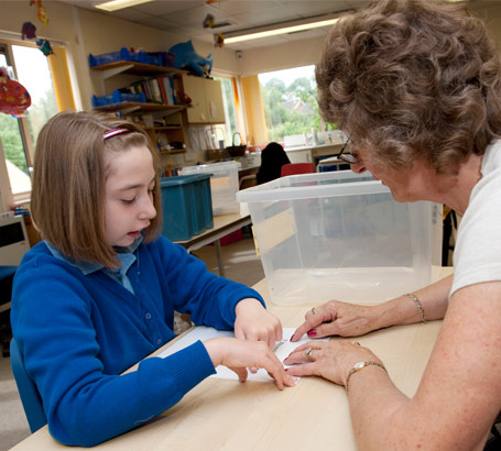 Teacher helping a girl read