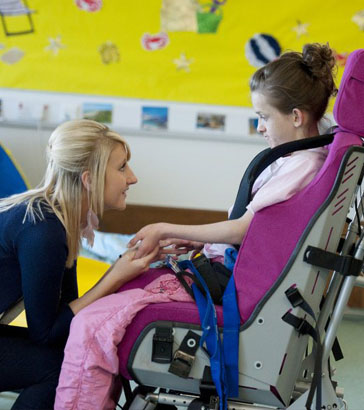 Teacher helping a disabled girl play with
a spinning top