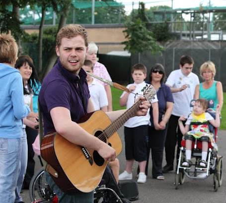 Teacher playing the guitar in front of
children