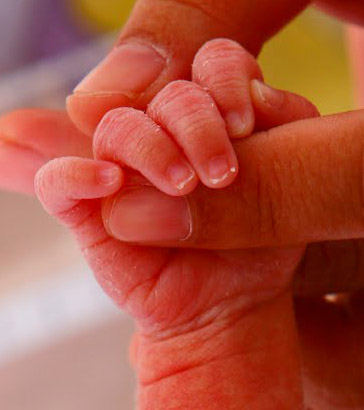 Newborn holding mother's
finger.