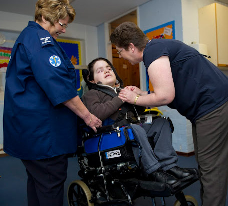 Teacher holding a disabled boy's
                  hands