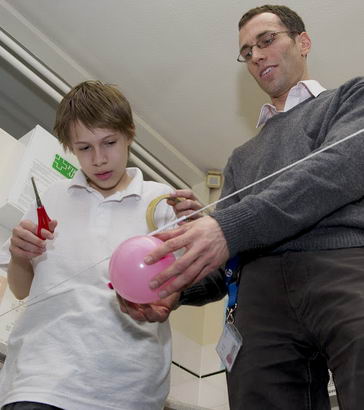 A science teacher helps a boy
with an experiment