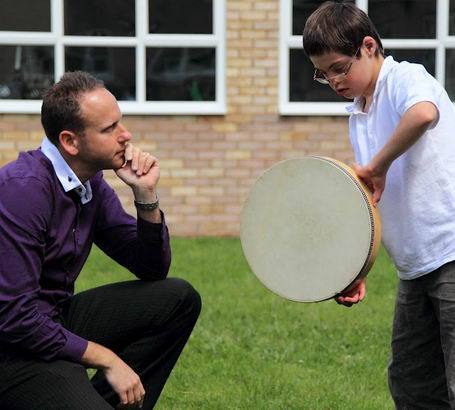 A teacher watches a boy play with a large
drum