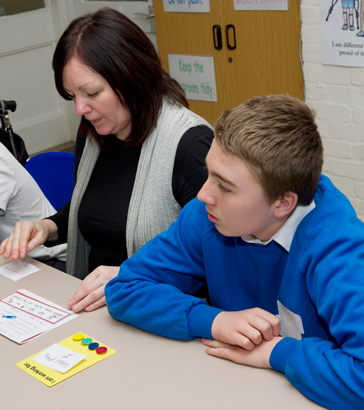 A teacher and some children sit
                  at a table