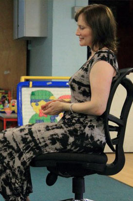 A teacher sits in front of a row of children