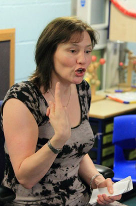 A teacher sits in front of a row of children